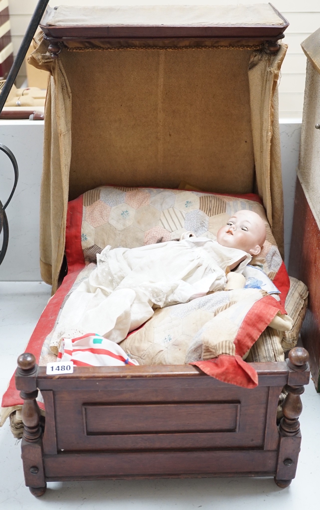 An Armand Marseille 390 A 11/2 M porcelain doll and a half tester wooded bed, bed 55cms deep x 55cms high x 36cms wide